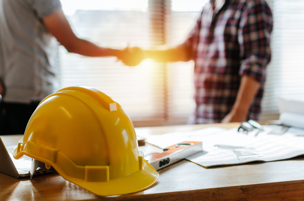 Contractor and client shaking hands in office